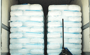 Stacks of bagged ice piled high inside a truck, ready for transportation.