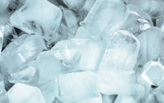 A close-up image of numerous clear ice cubes piled together, showcasing different sizes and shapes with visible cracks and frosty surfaces.