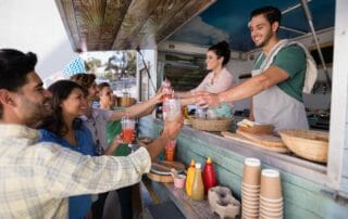 Group of people receiving drinks from vendors at a food truck.