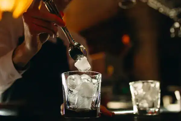 A bartender drops cubes in a glass