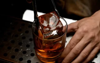 A bartender adds ice to a drink